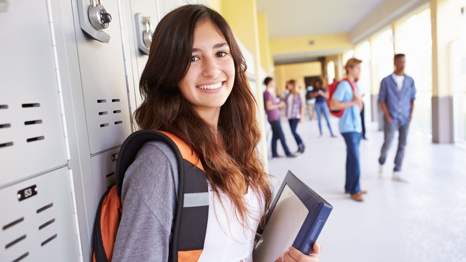 Female high school student standing in front of a locker